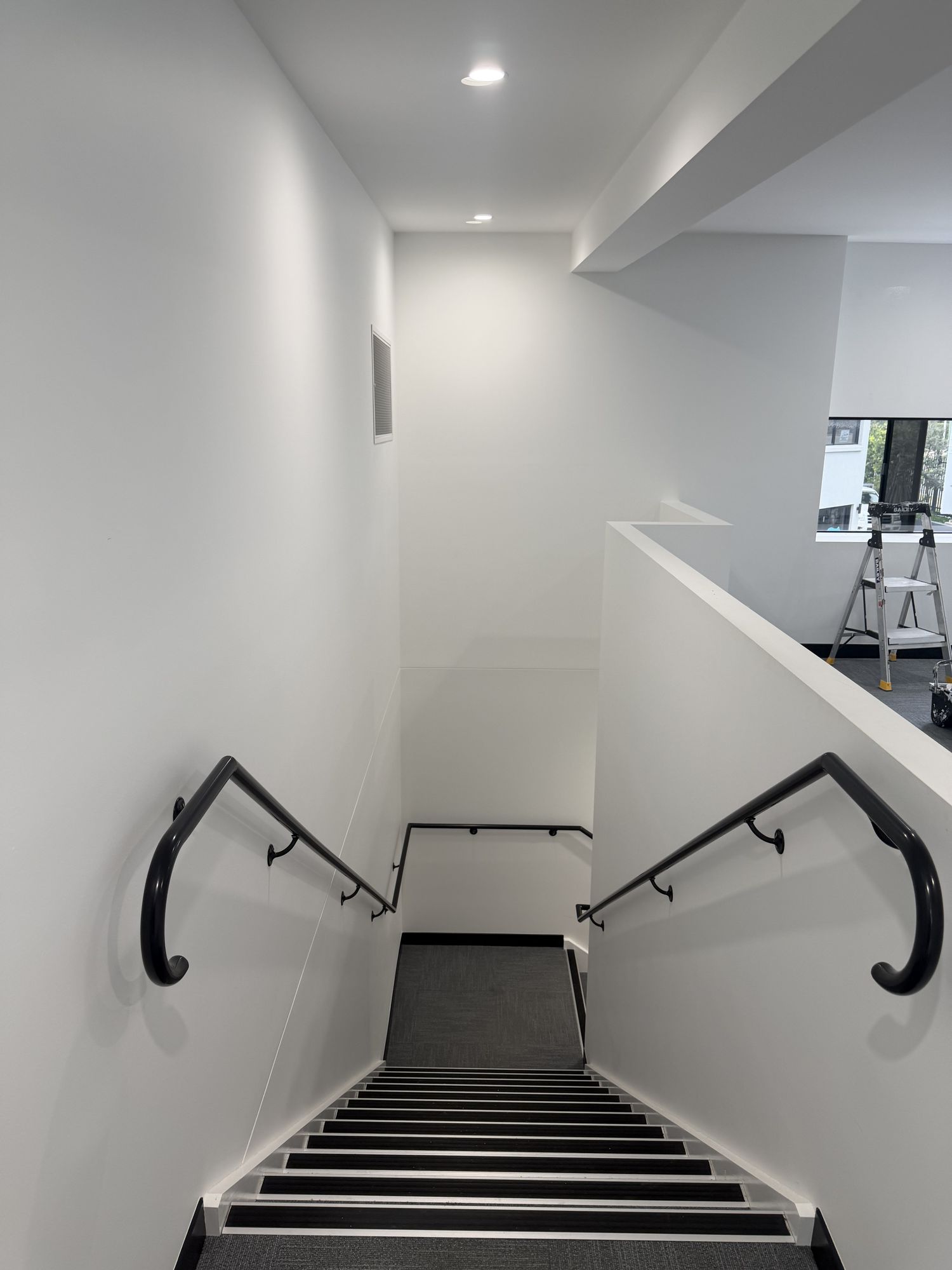 Freshly painted open-plan office space with white walls and dark carpet
