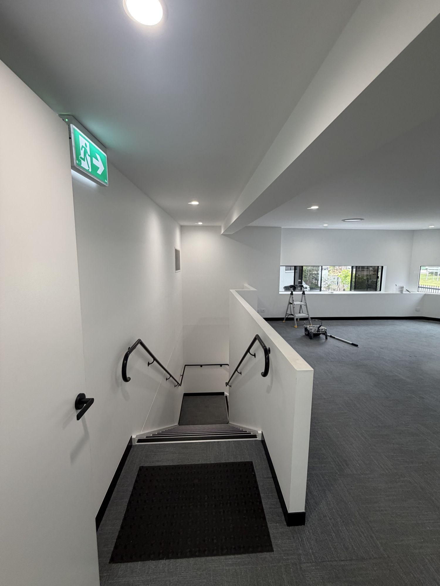 Freshly painted open-plan office space with white walls and dark carpet