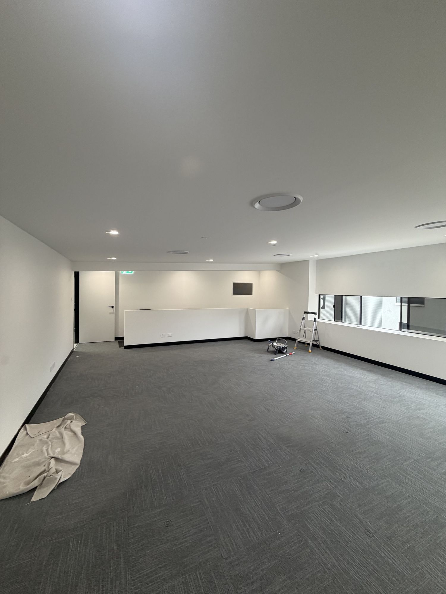 Freshly painted open-plan office space with white walls and dark carpet
