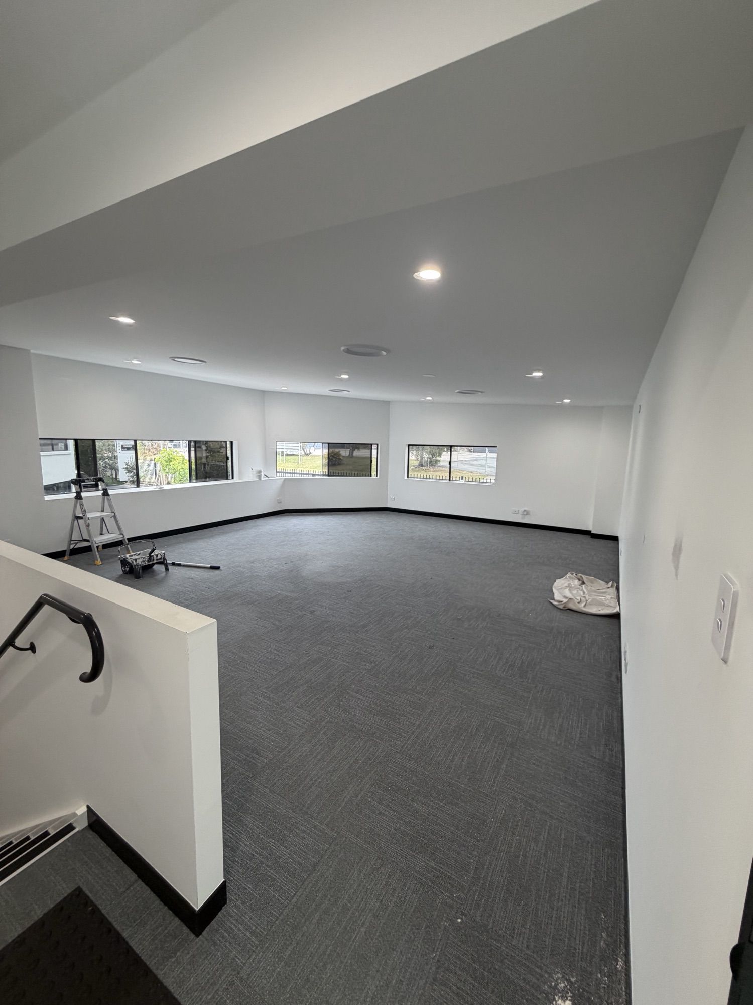 Freshly painted open-plan office space with white walls and dark carpet